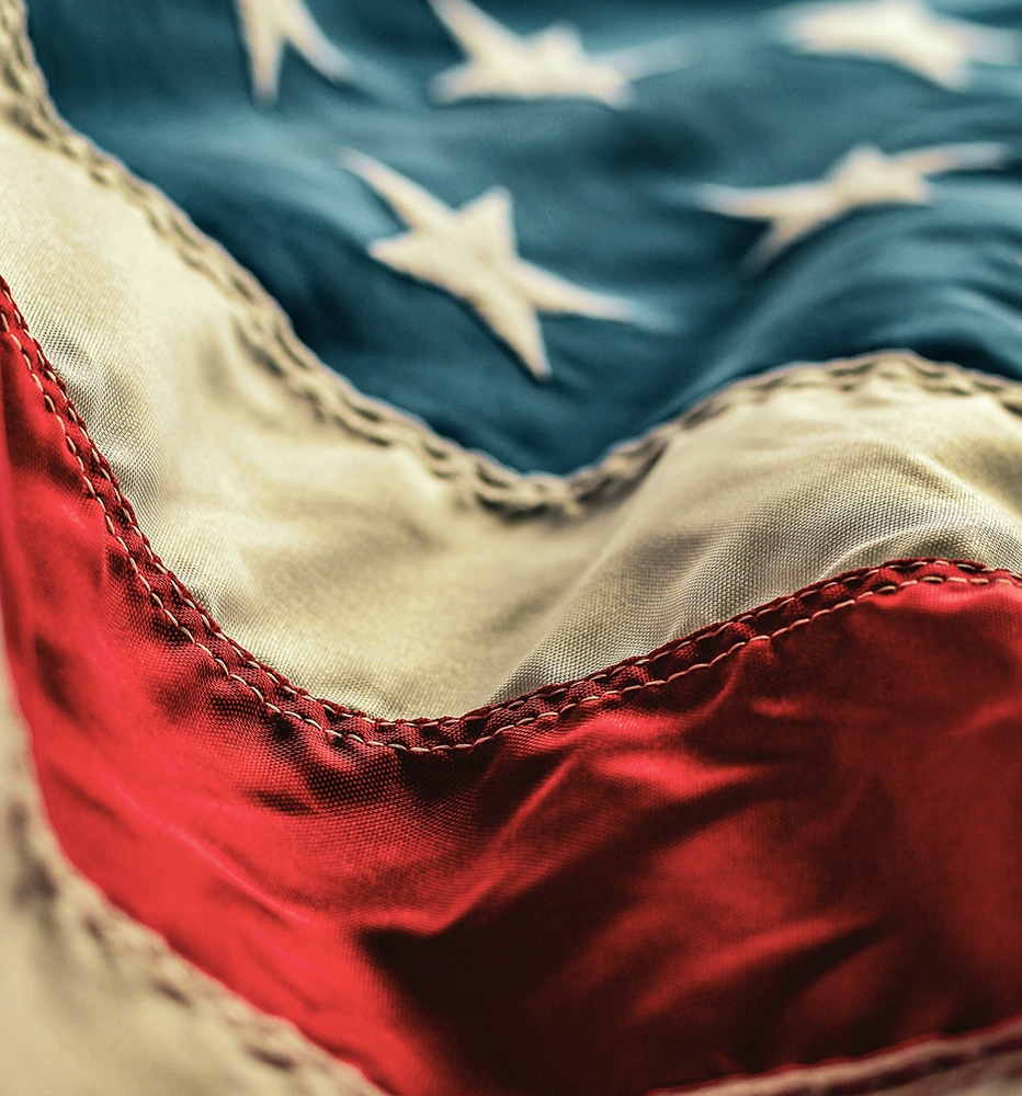 A close-up of an American flag, its stars and stripes lit from the side
