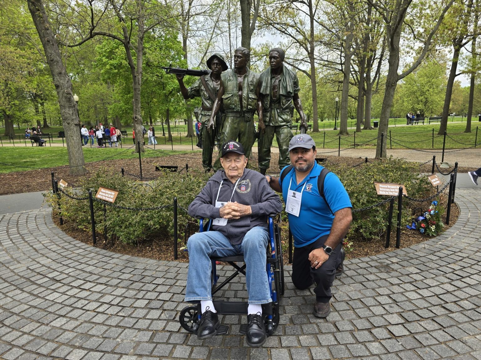 A veteran in a wheelchair and a volunteer beside him at the Three Servicemen statue at the Vietnam Veterans Memorial