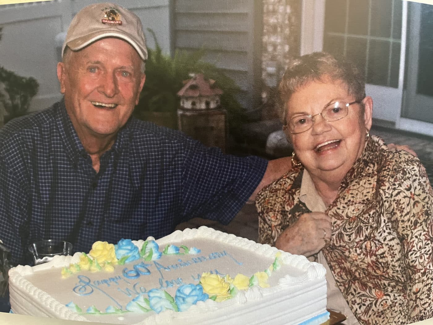 Ron and his wife smiling together behind an anniversary cake